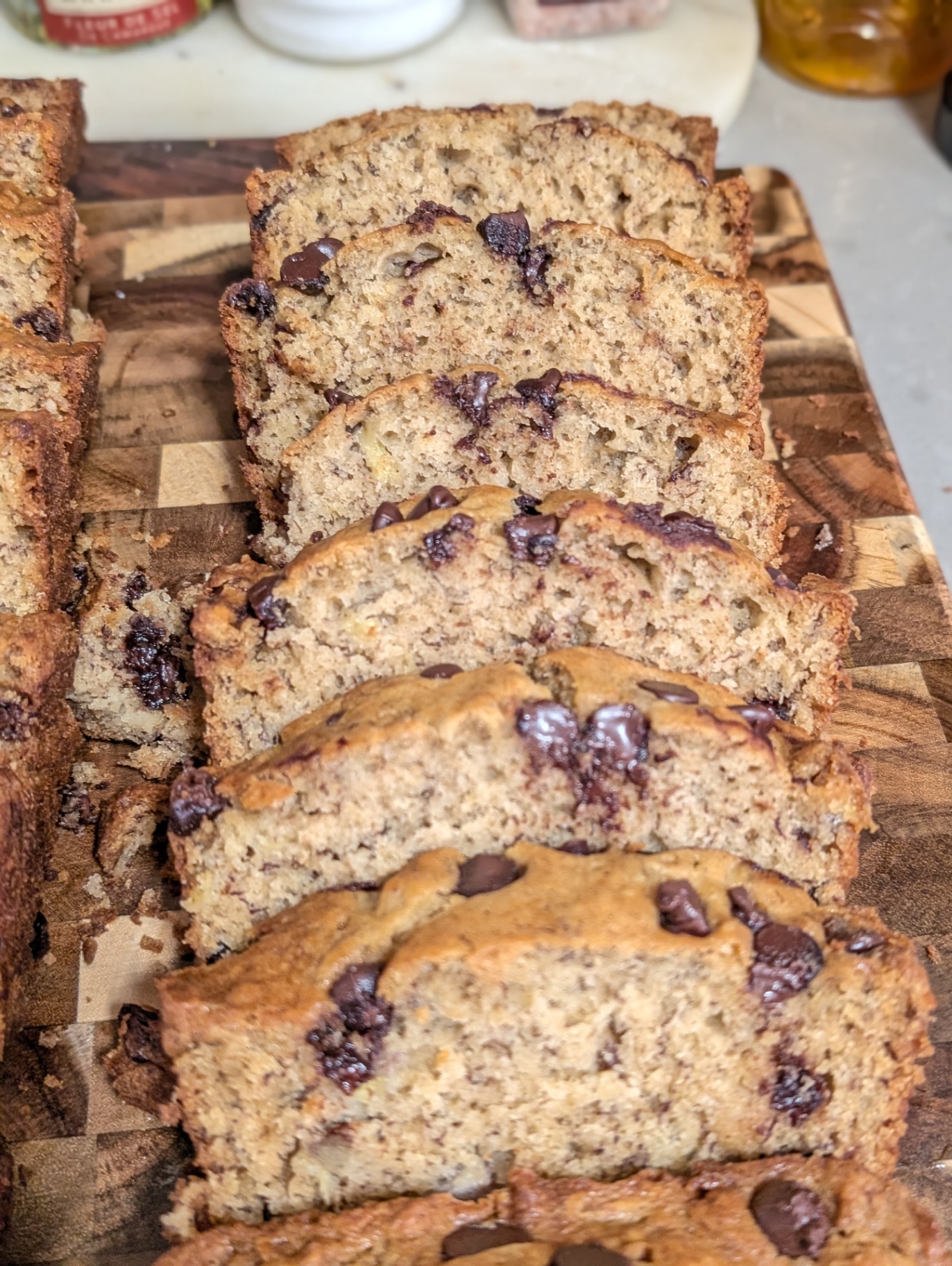 Slices of chocolate chip banana bread shingled down a wooden board